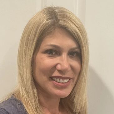 Smiling woman with blonde hair against a plain background.