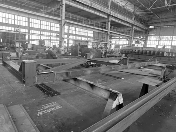Large metal beams being assembled inside an industrial factory.