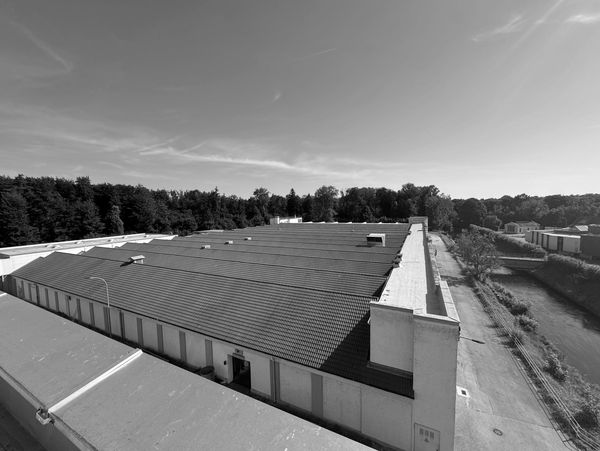 Large industrial building with red roof under clear blue sky.