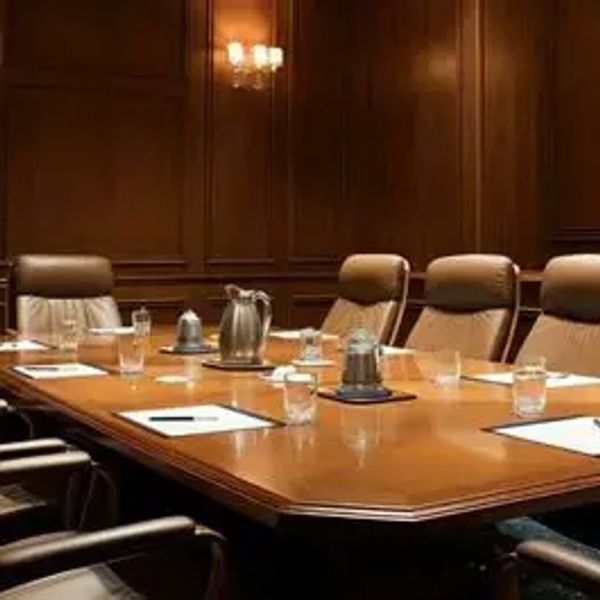 Salle de réunion avec table en bois et chaises en cuir.