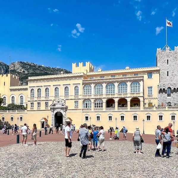 Touristes devant un palais historique sous un ciel bleu.