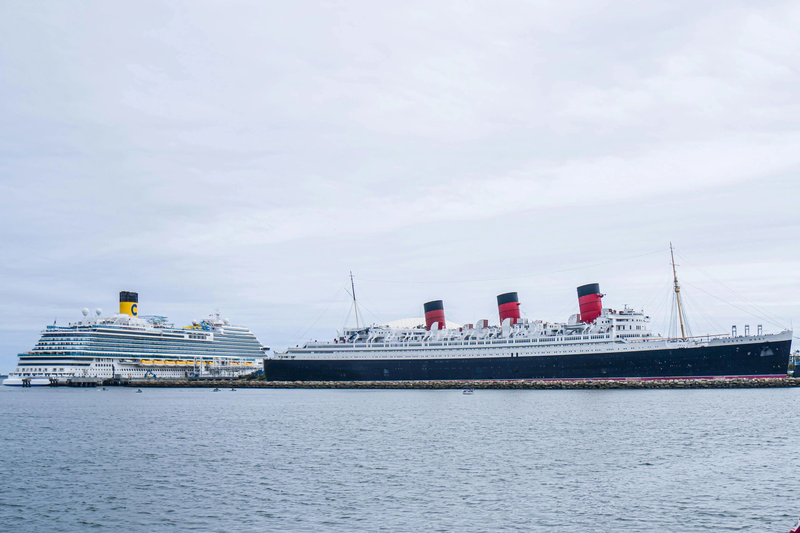 Two large cruise ships docked side by side under a cloudy sky.