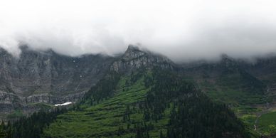 Foggy mountain peaks with lush green forest below.
