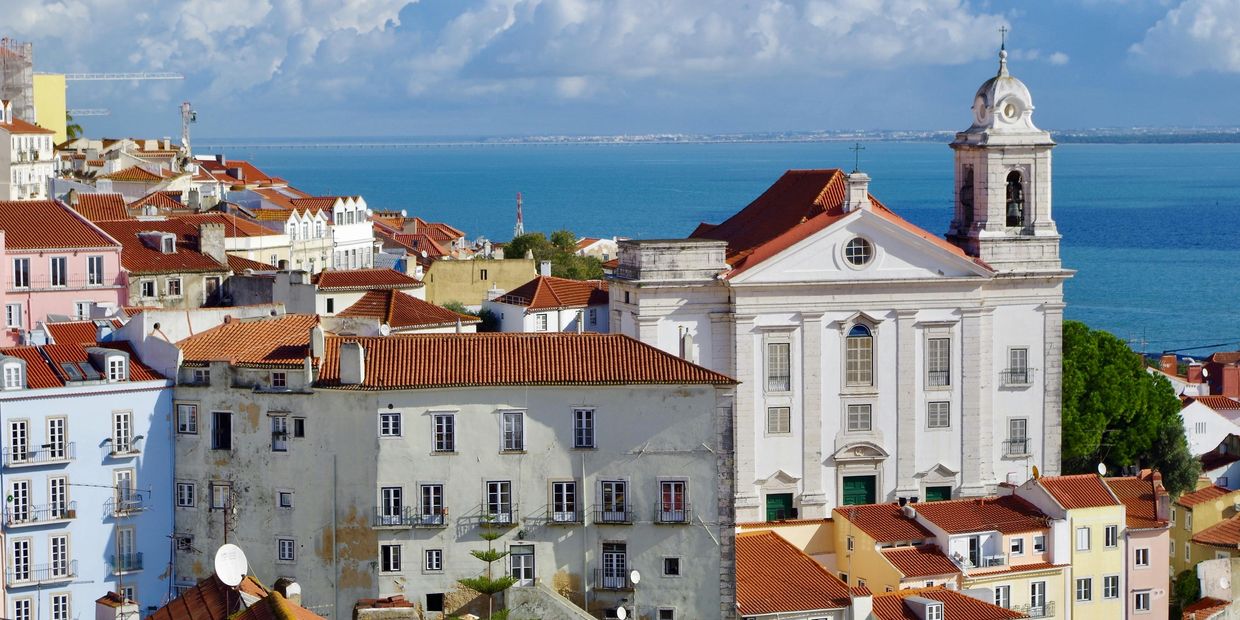 Seaside town with red-roofed buildings and a church.
