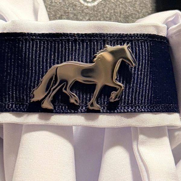Metal horse pin on navy and white fabric.