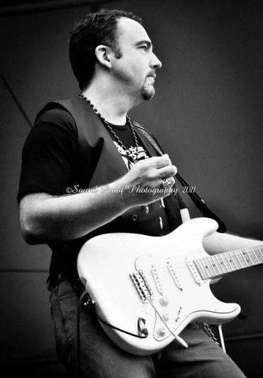 Musician playing electric guitar, captured in black and white.