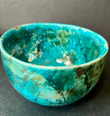 Turquoise ceramic bowl with a rustic finish.