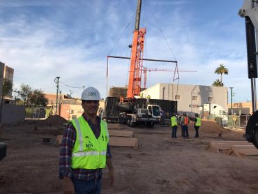 Construction worker posing at a job site with crane.
