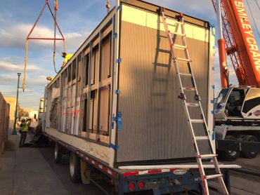 Crane loading a modular building onto a truck.