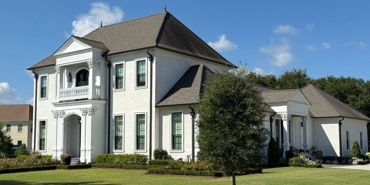 Large white two-story house with classic architecture and a manicured lawn.