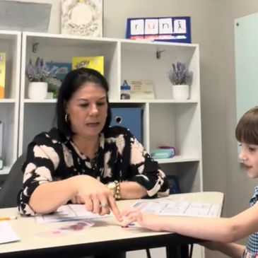 Teacher assisting a young student at a desk.
