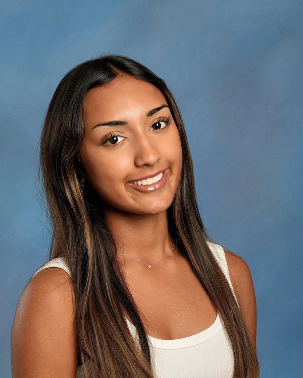 Young woman with long hair smiling against a blue background.