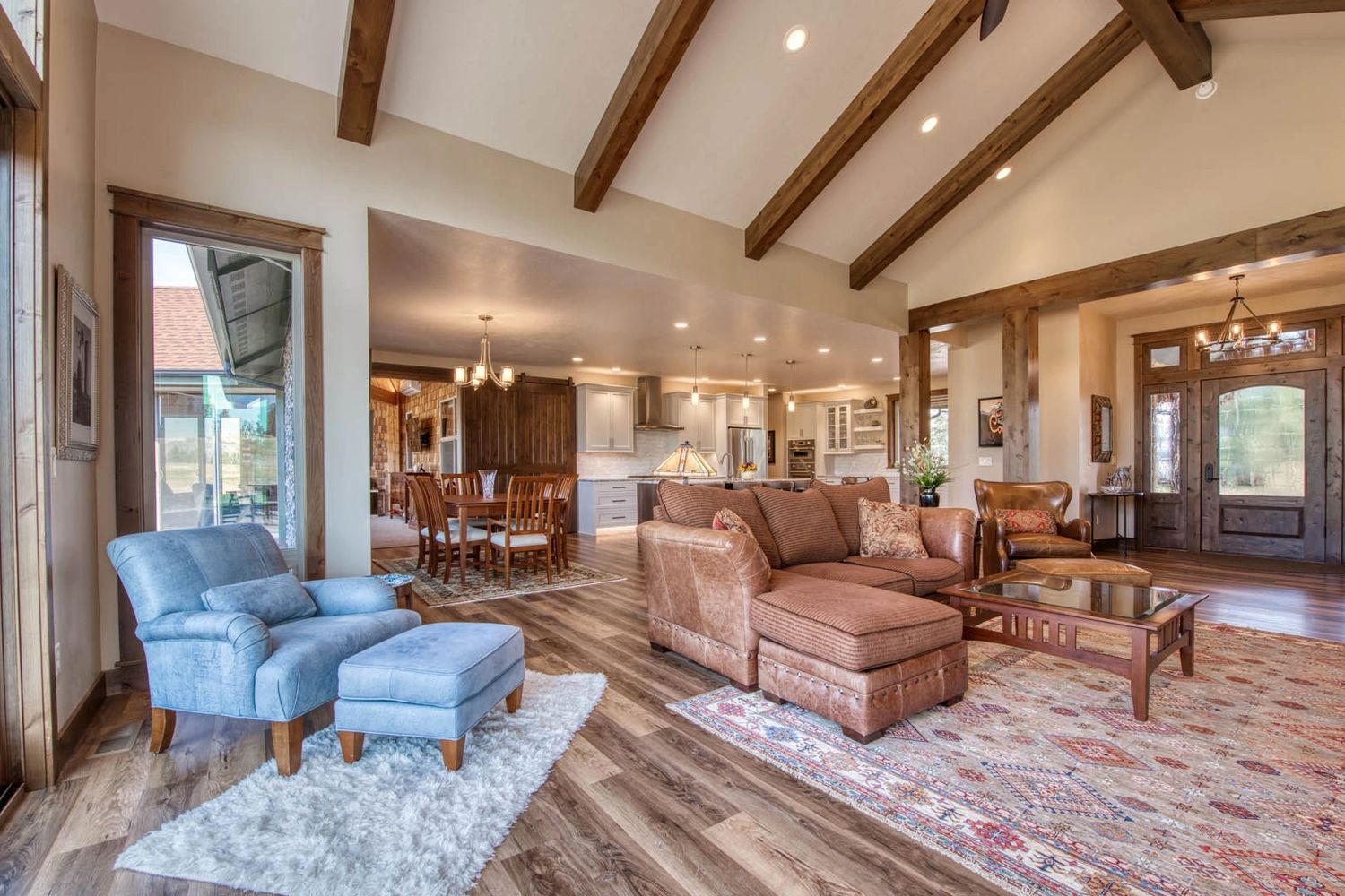 Cozy living room with a mix of blue and brown furniture under accented ceiling with stained wooden beams.