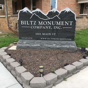 Stone sign for Biltz Monument Company with mountain design.