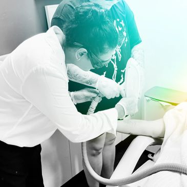A technician performs a laser treatment on a patient's leg.