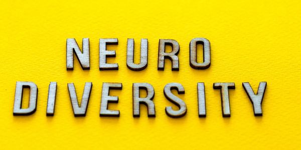 Wooden letters spelling 'NEURODIVERSITY' on a bright yellow background.