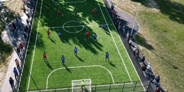 Aerial view of a soccer match on a small field with spectators.
