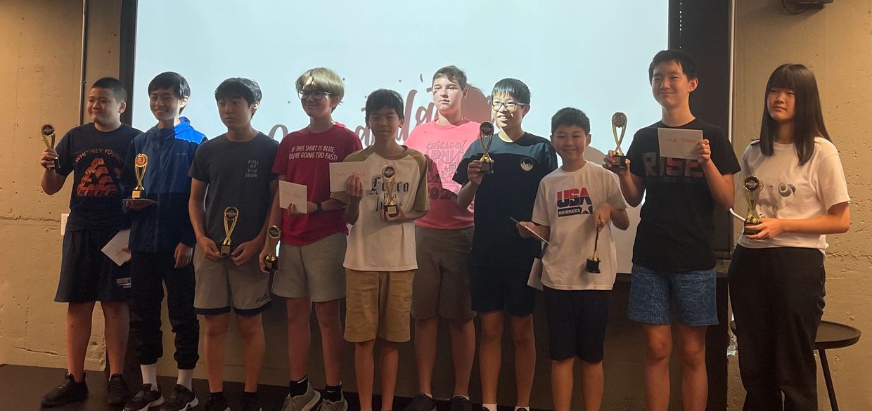 Group of young students holding trophies and certificates, celebrating achievements.