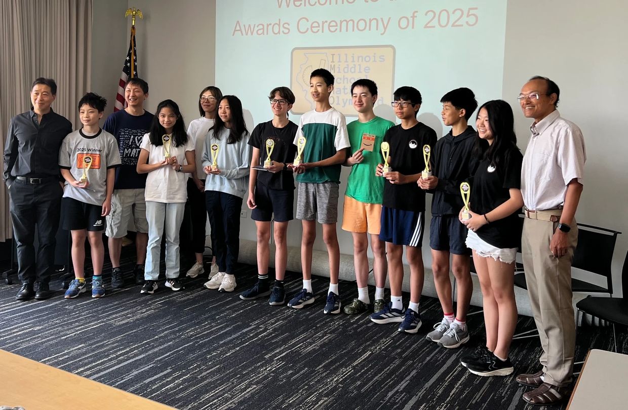Group of middle school students and adults holding trophies at 2025 awards ceremony.