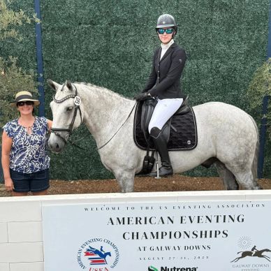 Equestrian rider in competition attire on a white horse at American Eventing Championships.