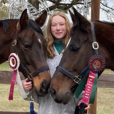 Young woman posing with two award-winning horses.