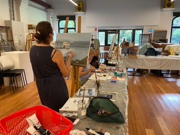 People painting on canvases in an art class studio.