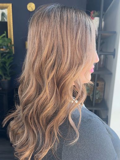 Side profile of a woman with long, wavy, light brown hair.