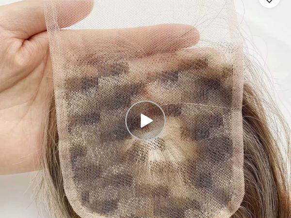 Hand holding a lace frontal wig piece showing hair knots under the mesh.