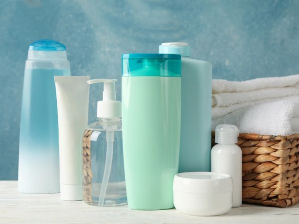 Various skincare bottles and containers arranged with folded towels in a wicker basket.