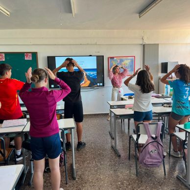Estudiantes y profesora haciendo ejercicio en clase.