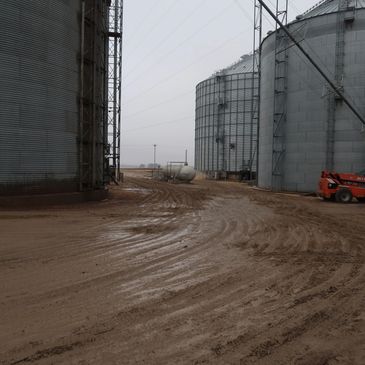 Grain storage bins and rough terrain material handler on dirt road