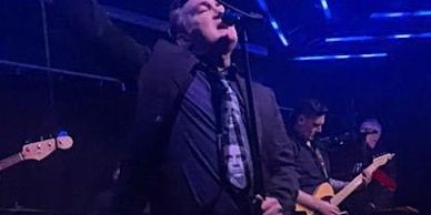 Male singer passionately performing on stage with band.