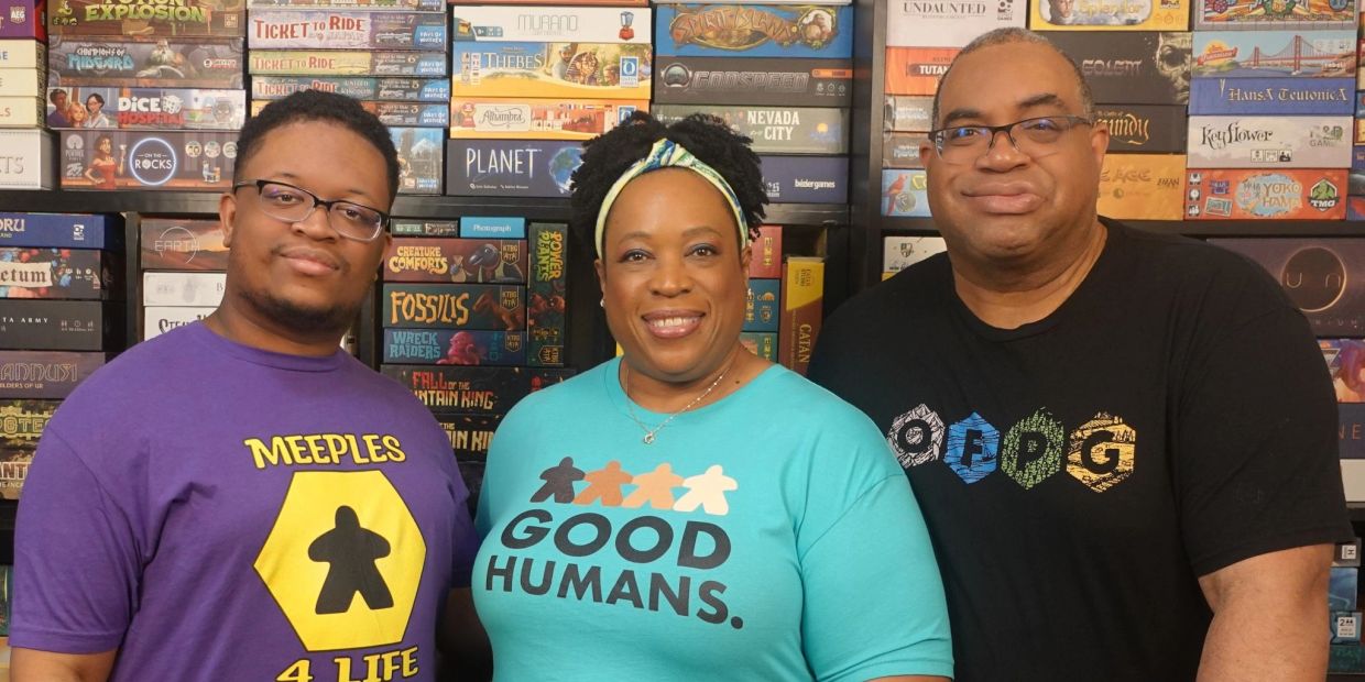 Three people smiling with board games behind them.