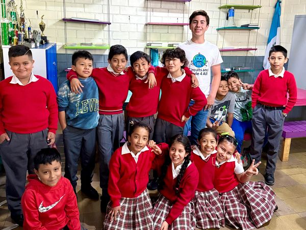 Group of smiling schoolchildren and a teacher posing in a classroom.
