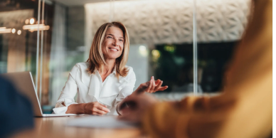 Smiling woman in white blouse talking in an office.