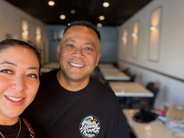 Two smiling people taking a selfie in a warmly lit room.