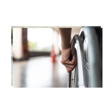 Hand gripping the wheel of a wheelchair.