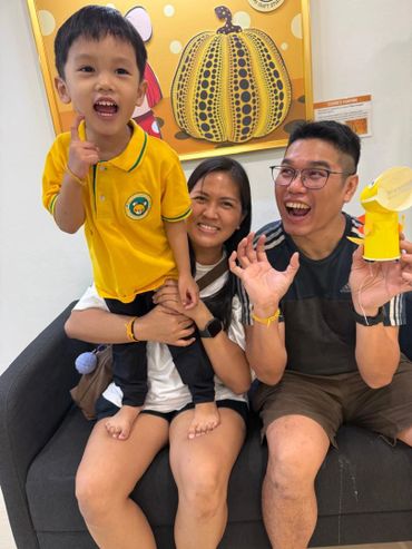 A joyful family posing with a child in a yellow shirt and playful expressions.