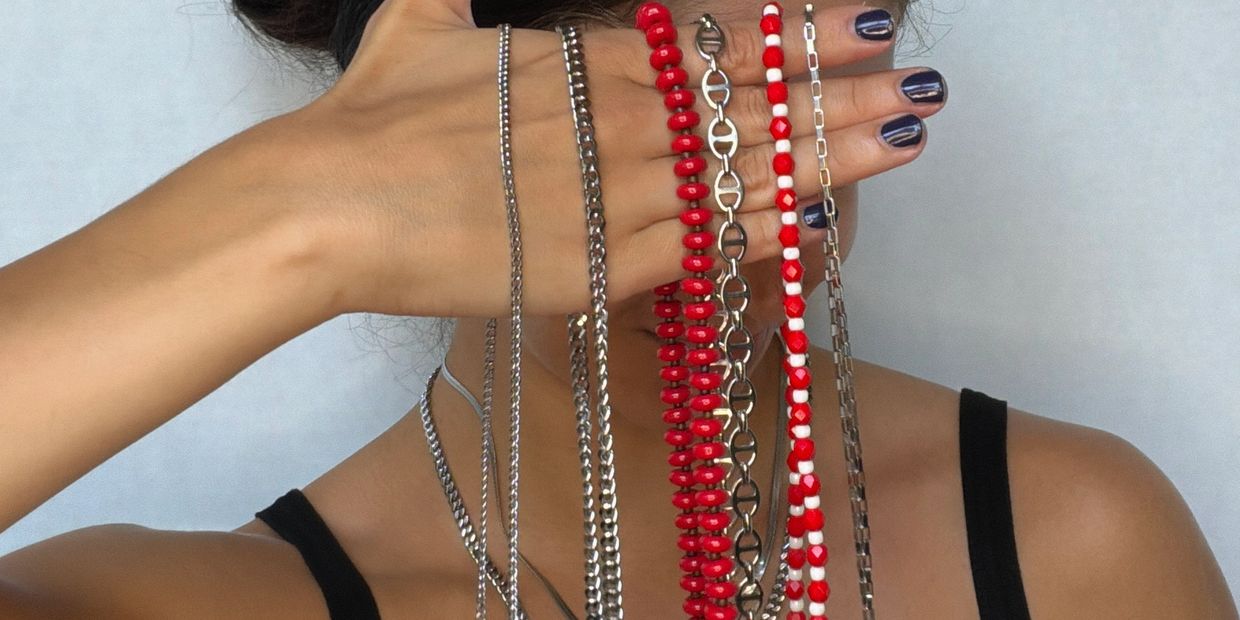 Hand holding several necklaces of different designs and colors.
