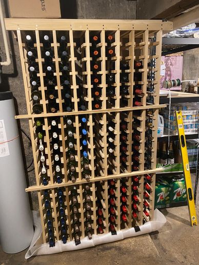 Wooden wine rack filled with bottles in a basement storage area.