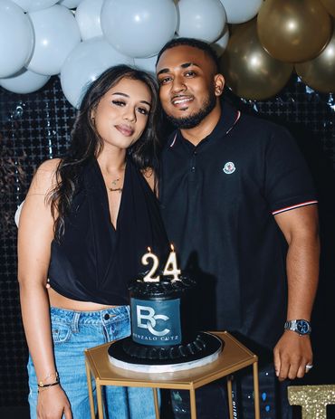 Couple celebrating 24th birthday with cake and balloons.