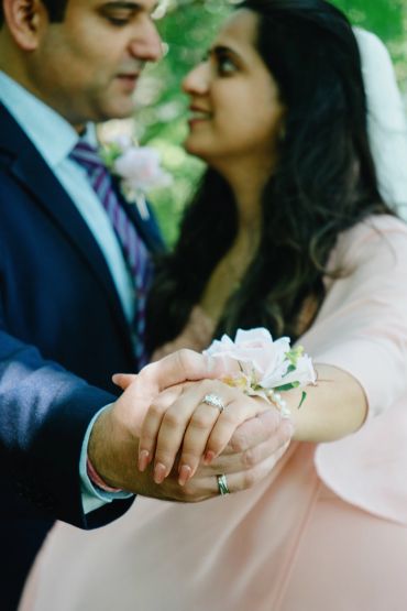 Newlywed couple holding hands showing their wedding rings.