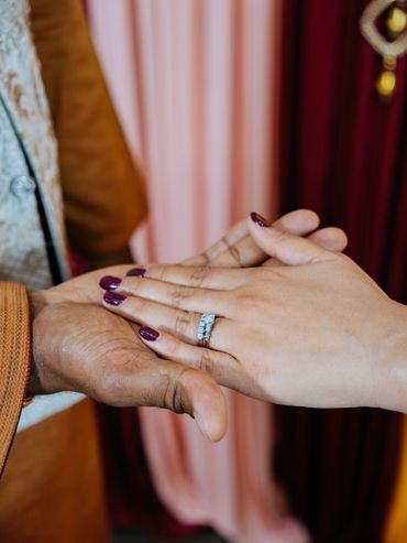 Two hands holding, one with a ring.