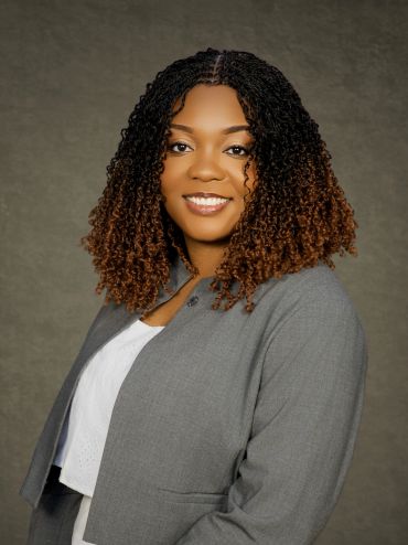 Professional portrait of a smiling woman with curly hair.