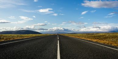 Open road stretching through a vast landscape under a blue sky.