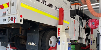 A large utility truck elevated on a hydraulic lift inside a workshop.
