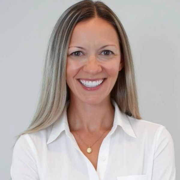 Smiling woman with long blonde hair in a white shirt.