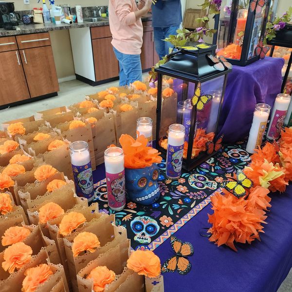 Day of the Dead altar with candles, marigolds, and decorative skulls on a purple cloth.
