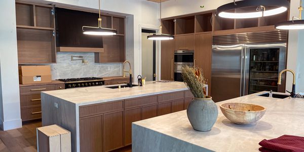 Modern kitchen with marble countertops and wooden cabinets.