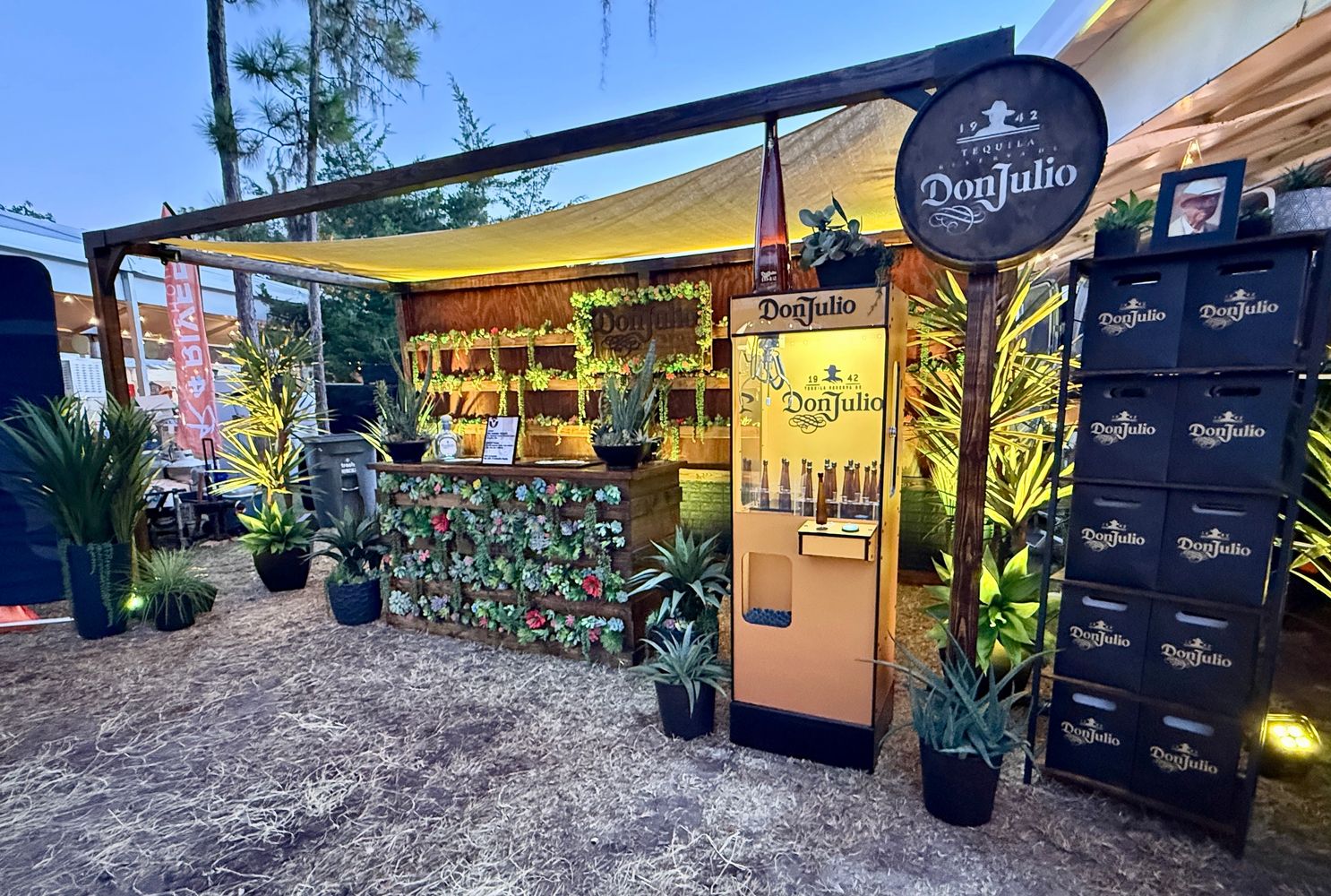 Evening Don Julio tequila booth decorated with plants and warm lighting.